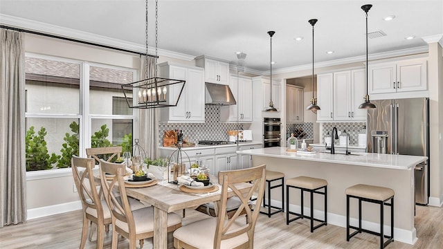 kitchen with visible vents, stainless steel appliances, a sink, under cabinet range hood, and backsplash