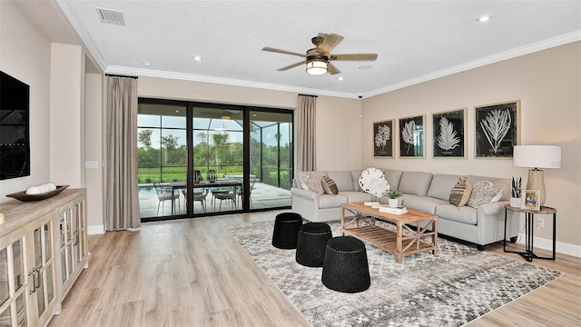 living area with visible vents, light wood-style flooring, baseboards, and ornamental molding