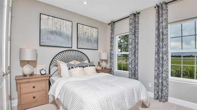 bedroom with baseboards, multiple windows, and light carpet