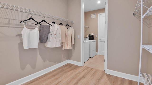 walk in closet with wood finished floors and washing machine and dryer