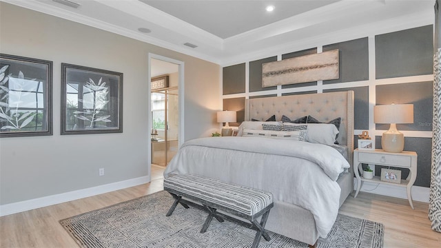 bedroom with light wood finished floors, visible vents, crown molding, baseboards, and a tray ceiling