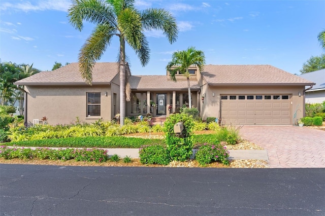 ranch-style house featuring decorative driveway, an attached garage, and stucco siding