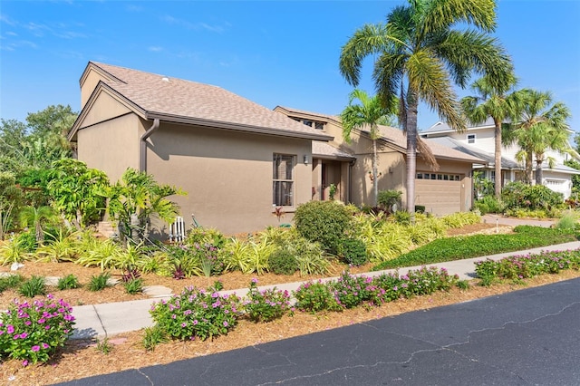 view of front of home with a shingled roof, a garage, and stucco siding