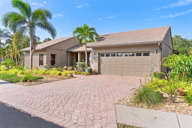 single story home with stucco siding, decorative driveway, and a garage