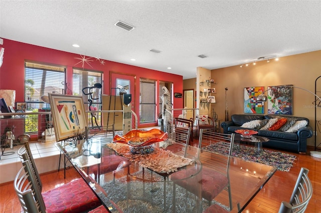 living room with visible vents, a textured ceiling, and wood finished floors