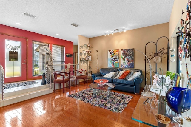 living area featuring visible vents, a textured ceiling, and wood finished floors