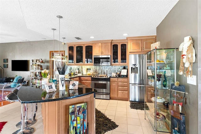 kitchen featuring light tile patterned floors, visible vents, glass insert cabinets, appliances with stainless steel finishes, and a kitchen breakfast bar