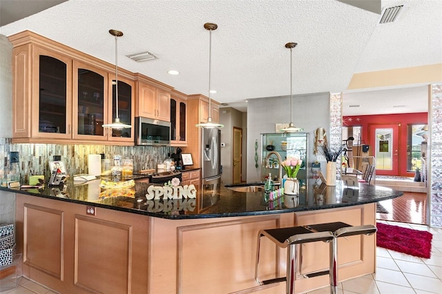 kitchen with visible vents, light tile patterned floors, decorative backsplash, appliances with stainless steel finishes, and a sink