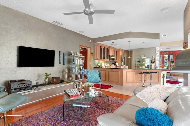 living area featuring visible vents, ceiling fan, and light wood-style floors