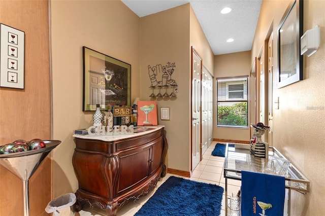 interior space with light tile patterned flooring, recessed lighting, a textured ceiling, and baseboards