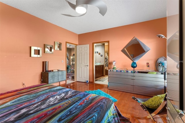 bedroom with ceiling fan, ensuite bath, wood finished floors, and a textured ceiling