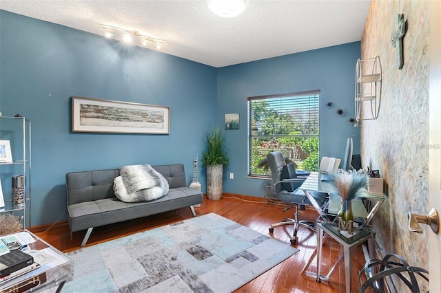 office area with hardwood / wood-style floors, baseboards, and a textured ceiling