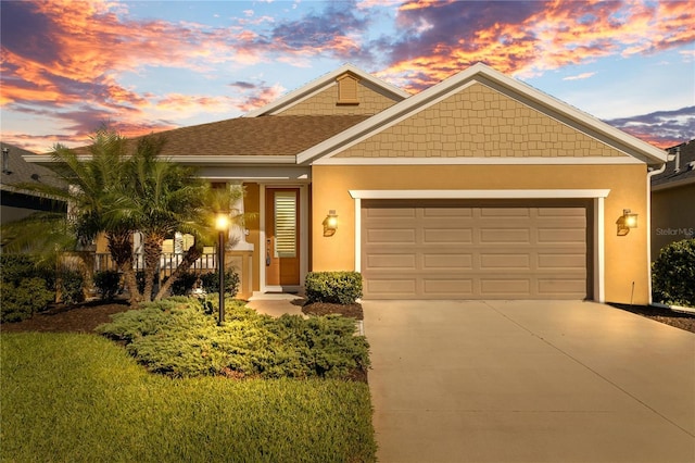 view of front of home with stucco siding, an attached garage, a shingled roof, and driveway