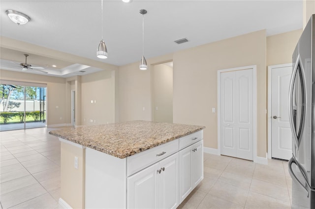 kitchen featuring visible vents, light stone countertops, pendant lighting, a tray ceiling, and freestanding refrigerator