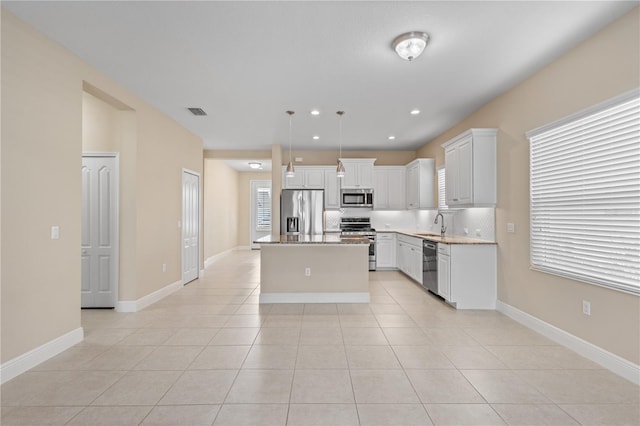 kitchen with a sink, a center island, stainless steel appliances, light tile patterned flooring, and hanging light fixtures