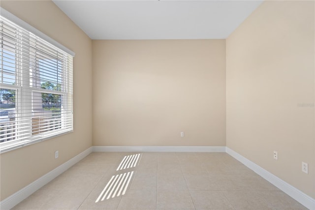 spare room with light tile patterned floors and baseboards