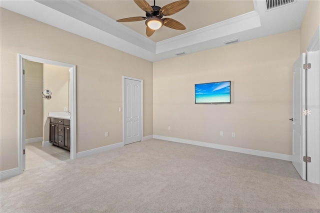 unfurnished bedroom featuring a tray ceiling, light carpet, visible vents, and ornamental molding