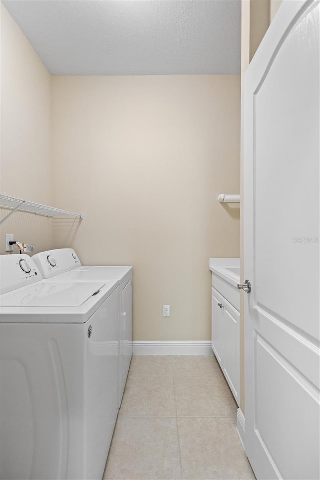 laundry room featuring washer and dryer, baseboards, cabinet space, and light tile patterned flooring