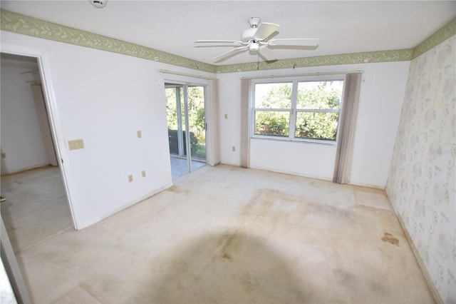 carpeted empty room featuring ceiling fan and wallpapered walls