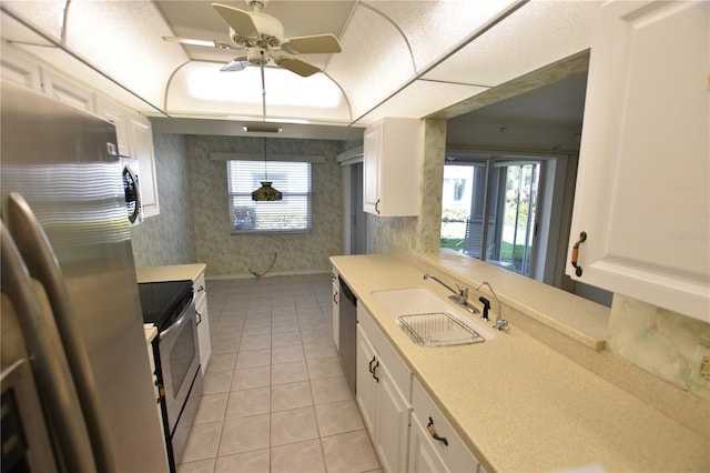 kitchen with wallpapered walls, a tray ceiling, stainless steel appliances, a sink, and light countertops