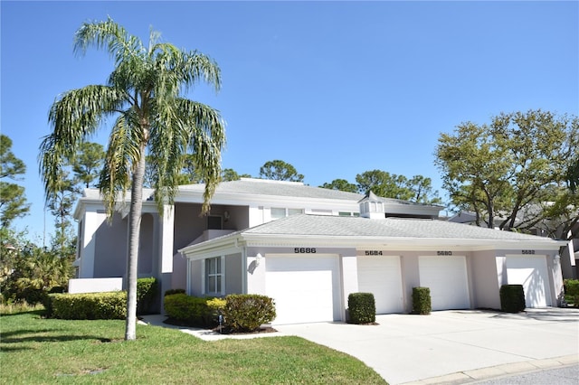 view of front of home featuring concrete driveway, a garage, a front yard, and stucco siding