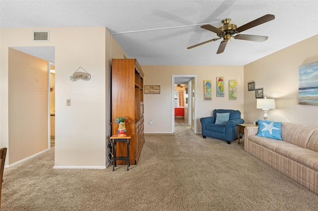 carpeted living room with baseboards, a ceiling fan, visible vents, and a textured ceiling