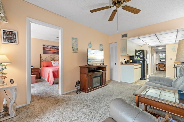 living area featuring a fireplace, light colored carpet, visible vents, and a ceiling fan