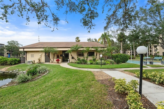 view of front of property with a front yard, fence, and stucco siding