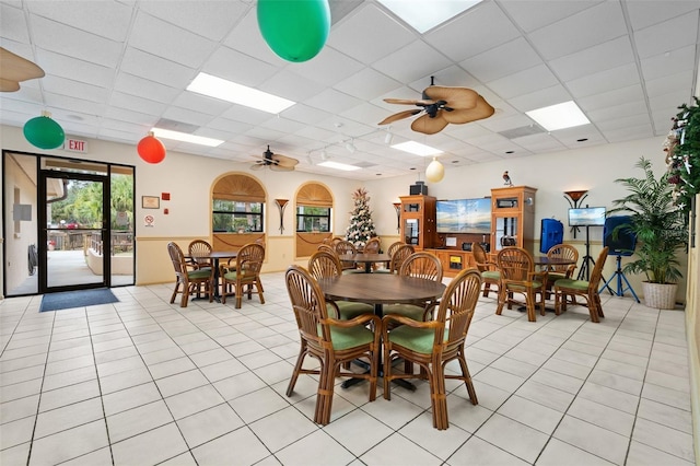 dining space with light tile patterned floors, a drop ceiling, and a ceiling fan