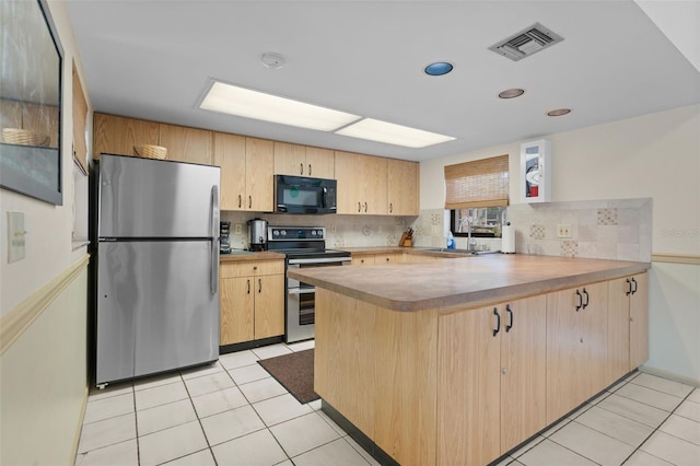 kitchen featuring light tile patterned floors, visible vents, a peninsula, a sink, and stainless steel appliances