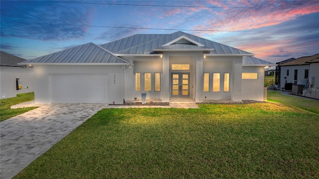 view of front facade with a front yard, stucco siding, french doors, decorative driveway, and a garage