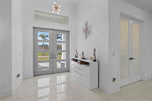 entryway featuring french doors, baseboards, marble finish floor, and an inviting chandelier