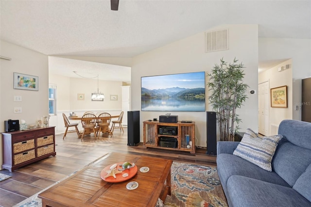 living area featuring visible vents, wood finished floors, and vaulted ceiling