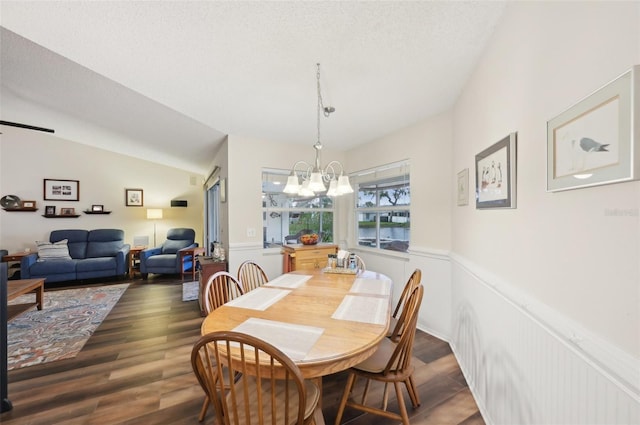 dining room with a notable chandelier, wood finished floors, wainscoting, and a textured ceiling