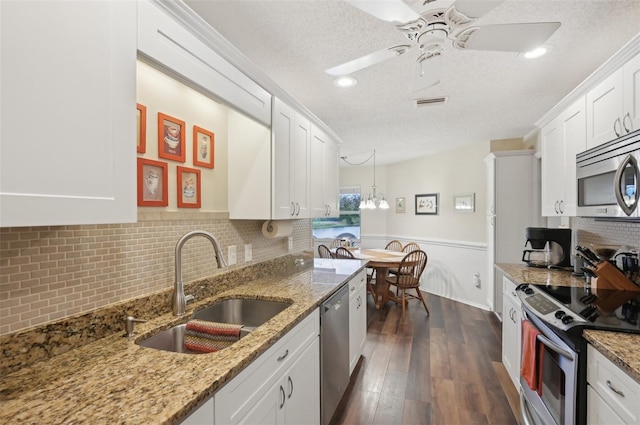 kitchen with dark wood-style flooring, a sink, stainless steel appliances, a textured ceiling, and white cabinetry