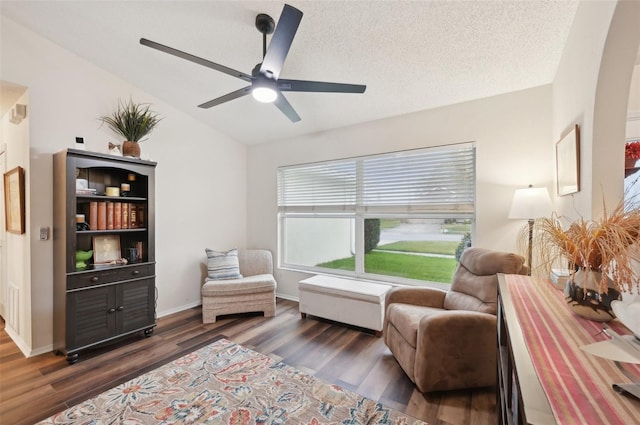 sitting room with lofted ceiling, a textured ceiling, wood finished floors, baseboards, and ceiling fan