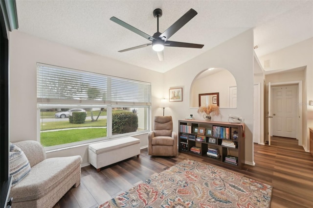 living area featuring lofted ceiling, a textured ceiling, wood finished floors, and a ceiling fan