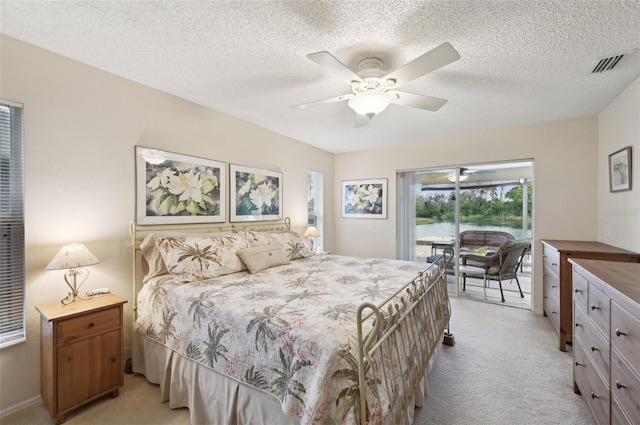 bedroom featuring a textured ceiling, access to exterior, visible vents, and light carpet