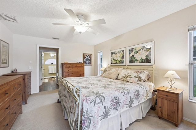 bedroom featuring visible vents, light carpet, and a textured ceiling