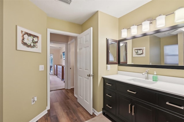 bathroom with vanity, visible vents, wood finished floors, and baseboards