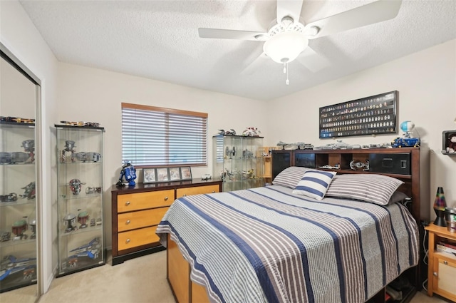 bedroom with a closet, light carpet, a textured ceiling, and a ceiling fan