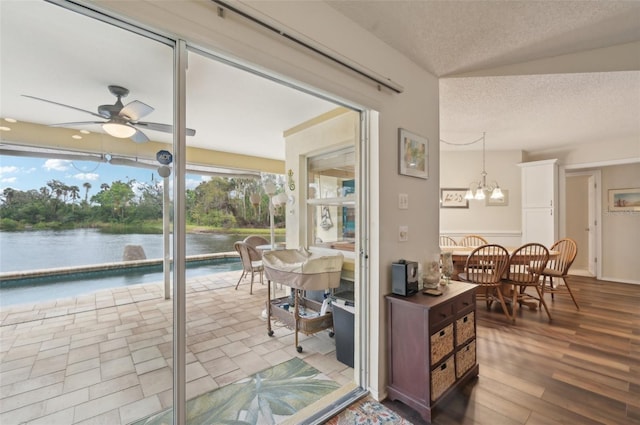 sunroom featuring a water view and ceiling fan with notable chandelier