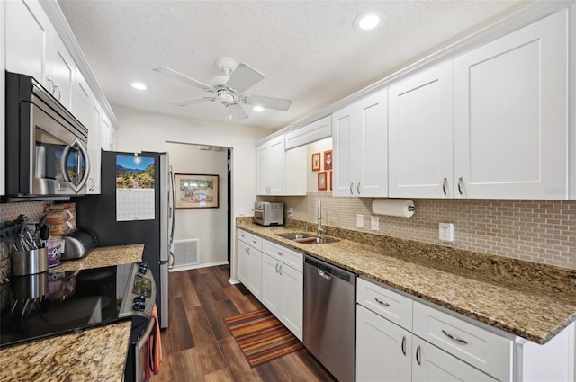 kitchen featuring appliances with stainless steel finishes, white cabinetry, dark wood-type flooring, and a sink