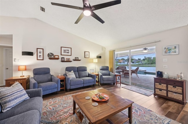 living area featuring visible vents, lofted ceiling, wood finished floors, a textured ceiling, and a ceiling fan