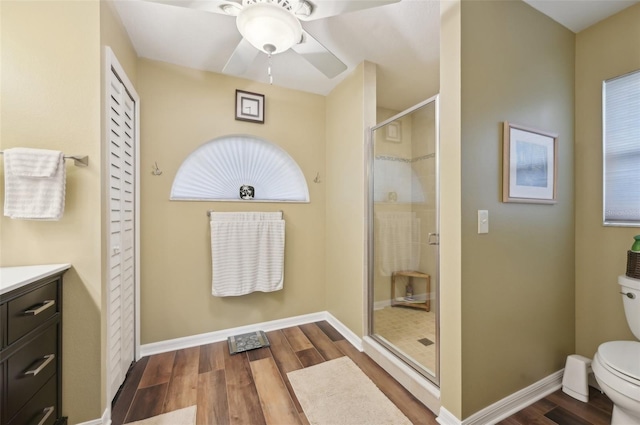 full bathroom with vanity, wood finished floors, baseboards, a stall shower, and toilet