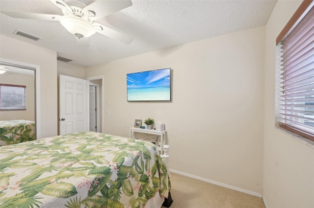 bedroom featuring visible vents, light colored carpet, and a textured ceiling