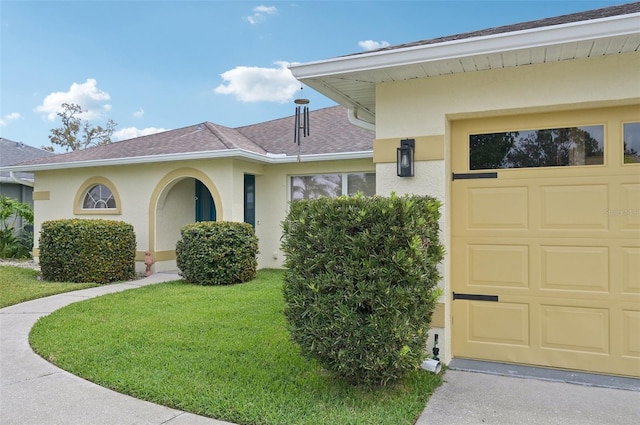 exterior space with a shingled roof, a front yard, a garage, and stucco siding