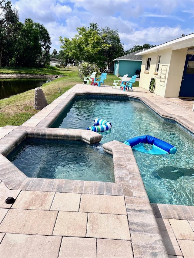 view of swimming pool with a lawn, a pool with connected hot tub, and a patio area