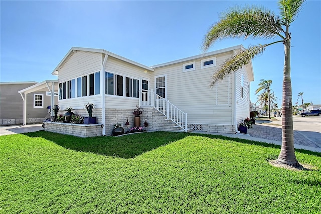 rear view of house featuring a yard and a sunroom