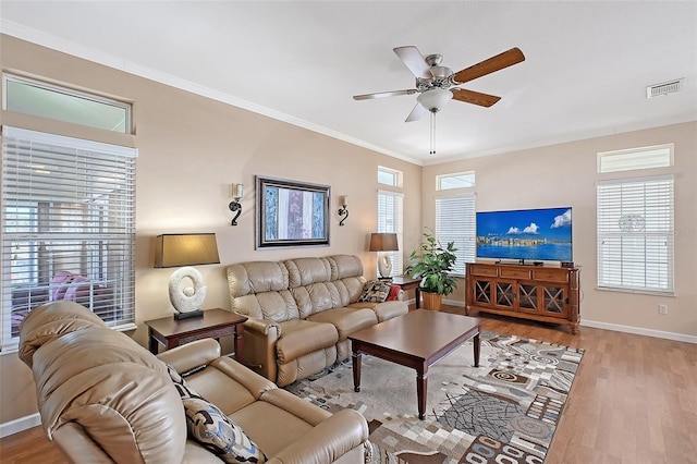 living area with crown molding, plenty of natural light, wood finished floors, and visible vents